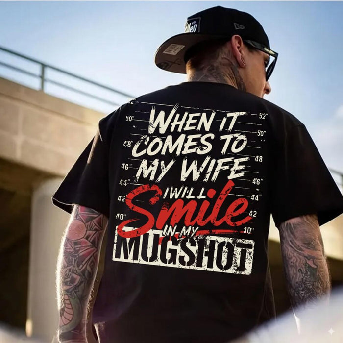 Man wearing a black t-shirt with a humorous graphic ( When it comes to my wife I will smile in my mugshot and text outdoors.
