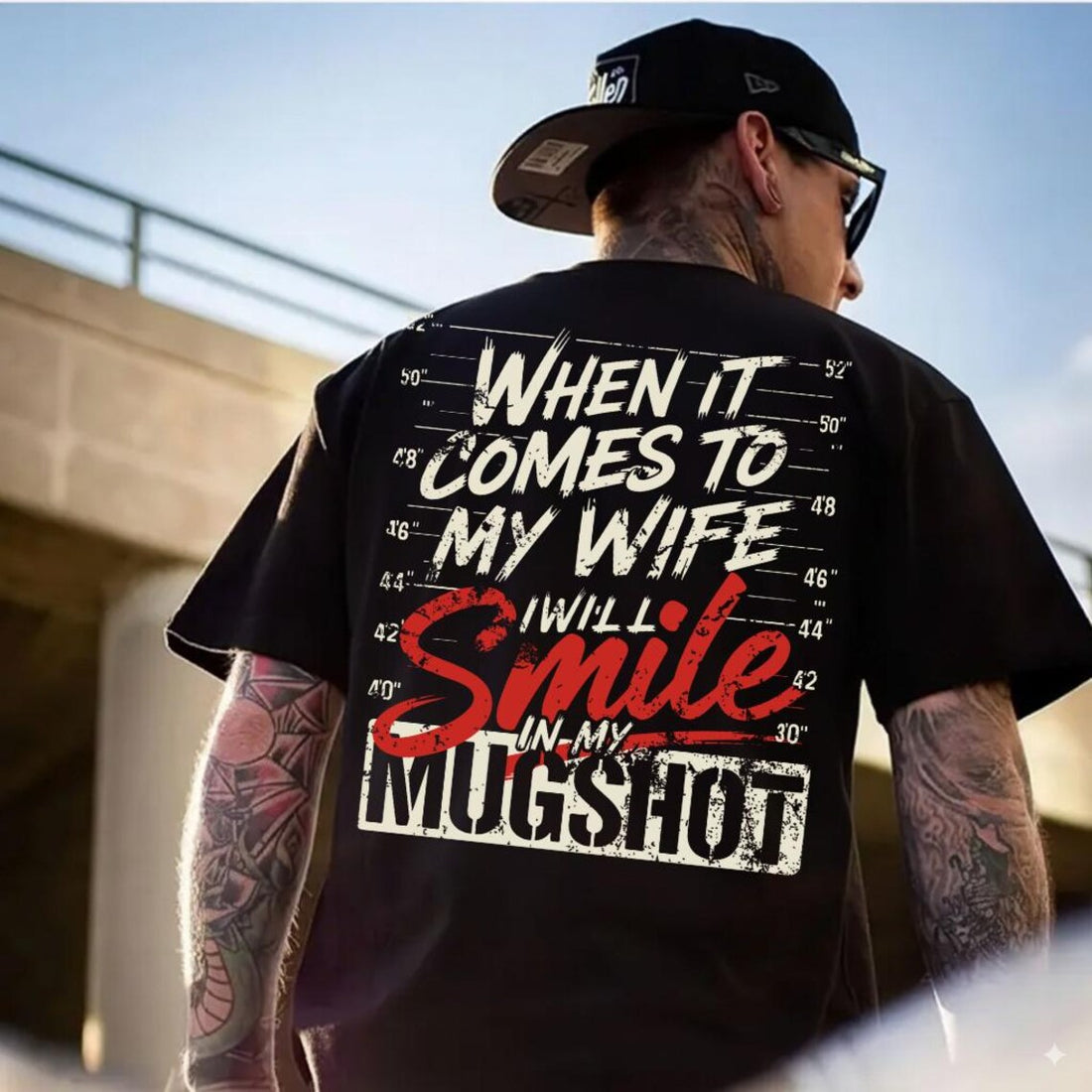 Man wearing a black t-shirt with a humorous graphic ( When it comes to my wife I will smile in my mugshot and text outdoors.